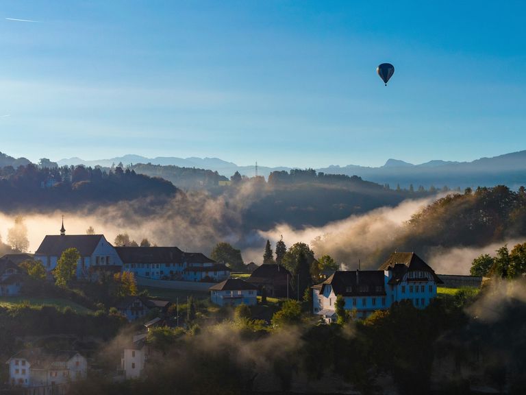 In dieser Podcast-Folge geht es nach Fribourg. Heißluftballon über Fribourg in der Schweiz