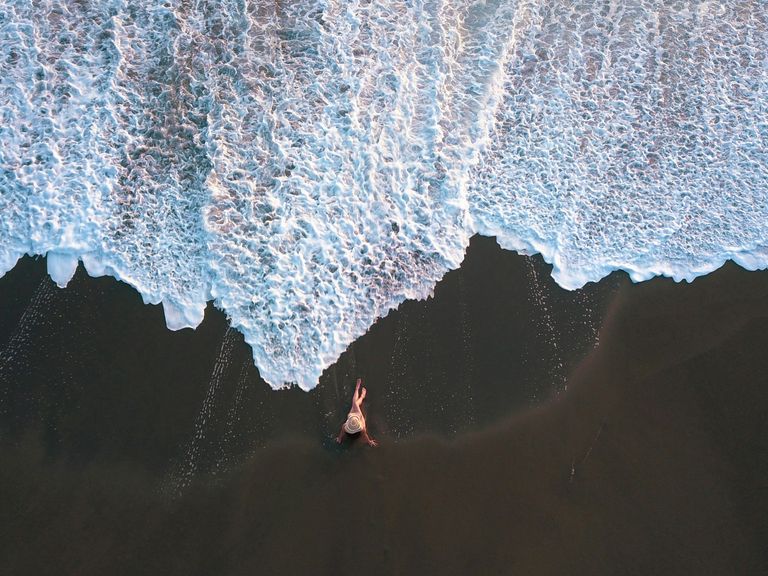 Costa Rica bietet vielfältige Landschaften, Strandabschnitte gehören genauso dazu wie Vulkane und Dschungel. Luftaufnahme einer Frau am Lavastrand in Costa Rica