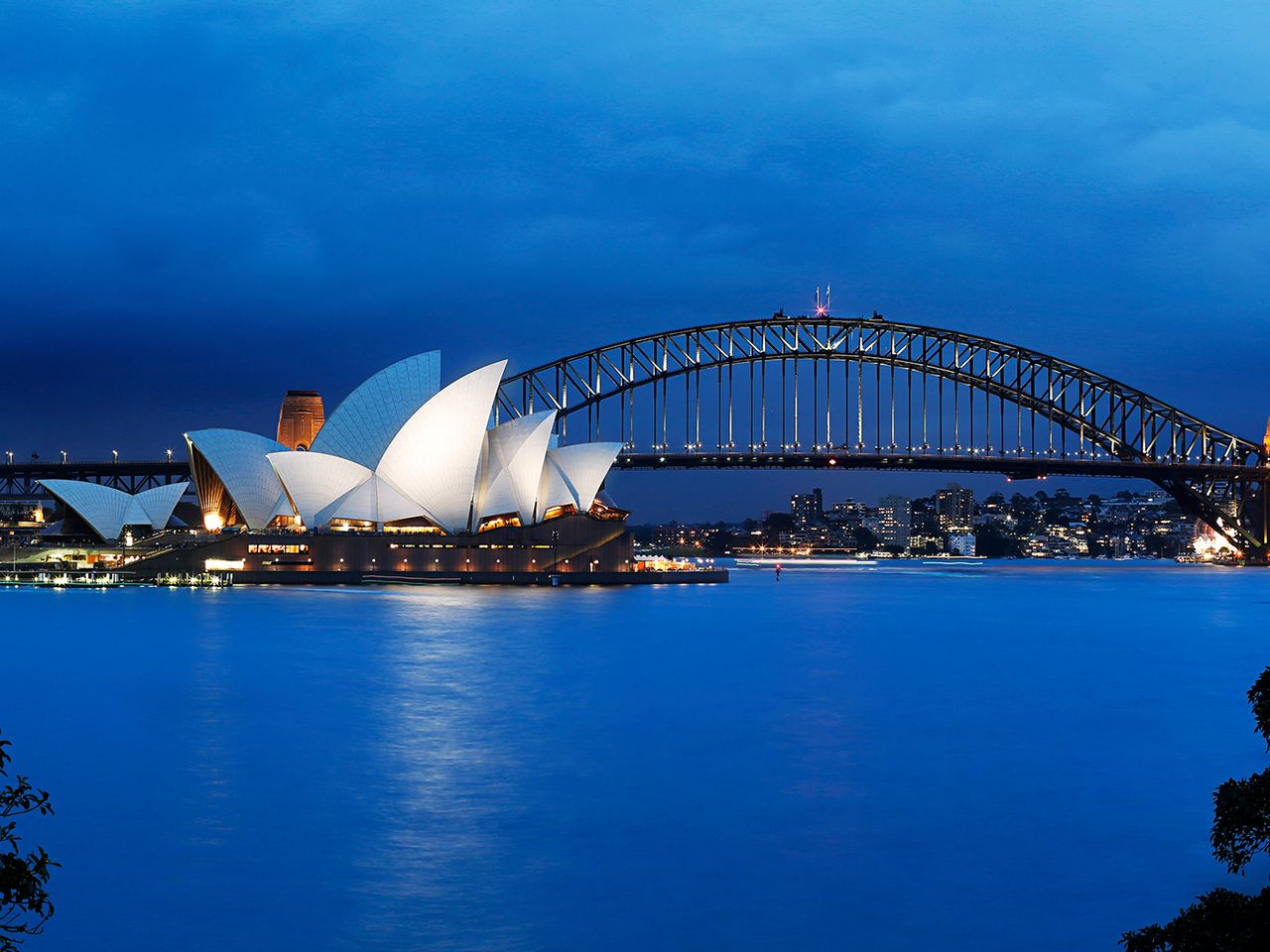 Der hell erleuchtete Hafen von Sydney mit Opernhaus.