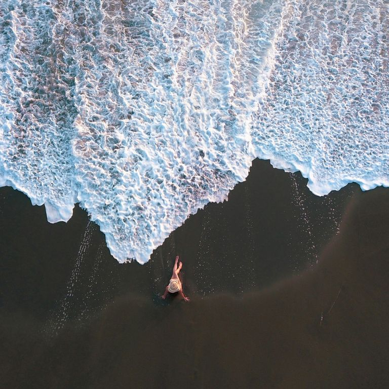 Costa Rica bietet vielfältige Landschaften, Strandabschnitte gehören genauso dazu wie Vulkane und Dschungel. Luftaufnahme einer Frau am Lavastrand in Costa Rica